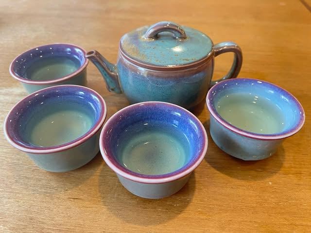 A glazed blue teapot and four tea cups